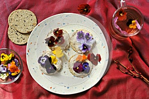 Edible flowers snacks with flower tea as a healthy and happy breakfast on a red background