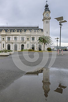 The Edificio del Reloj clock tower, port of Valencia, Spain, is reflected in a puddle of water photo