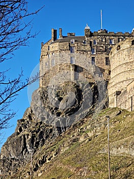 Edinburgh castle on rocky hill seen from below with bright blue sky behind