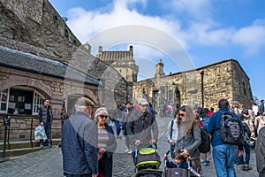 View at the interior Edinburgh Castle, detail of walls medieval fortress after principal gate, and tourists walking, on city of