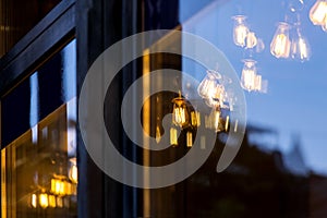 Edison lamps shine a warm light in the restaurant room behind the glass.