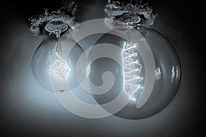 Edison light bulbs with a tungsten spiral in a vacuum close-up next to a concrete wall