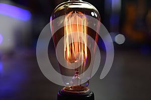 `Edison` a vintage incandescent light bulb with ultraviolet hues in the background