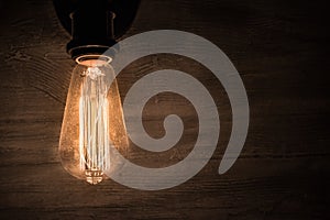 Edison vintage light bulb, retro light bulb in dark room and concrete wall as background photo