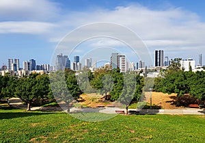 Edith Wolfson Park. Alley, wooden benches and green trees. Distance view from grassy park hill on Tel Aviv and  Ramat Gan