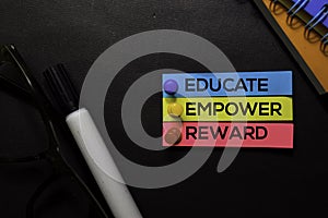 Educate, Empower, Reward text on sticky notes isolated on Black desk. Mechanism Strategy Concept