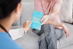 Educate yourself. Shot of a female nurse giving her patient a Covid-19 information pamphlet.