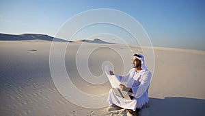 Educated male Muslim Arabian UAE Sheikh architect sits with gadget and drawing in hands, examines terrain for