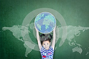 Educated school kid lifting world globe chalk doodle drawing on green chalkboard for education concept