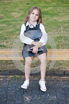 Educating tiny minds. Little kid in uniform sit on park bench. School fashion. Schoolwear. Elementary education