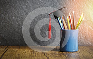 Education and back to school concept with graduation cap on pencils colour in a pencil case on dark