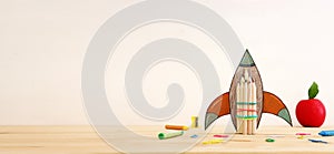 education. Back to school concept. rocket cut from paper and painted over wooden table and pastel background