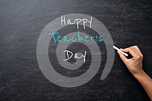 Education or back to school Concept. Woman hand holding chalk with Happy Teacher`s Day text over chalkboard background