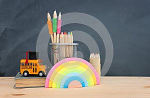 education and back to school concept. yellow bus, graduation hat and pencils over wooden desk