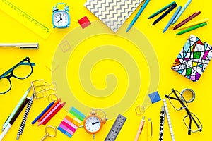 Education background, frame. School, student, office supplies. Stationery, glasses, alarm clock, notebook on yellow