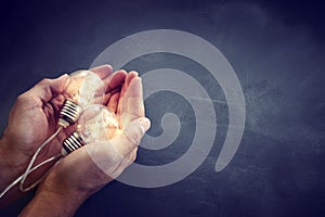 Education and business concept image. Creative idea and innovation. Man holding a light bulbs as metaphor over blackboard