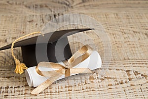 Education concept. Graduation hat with gold tassel, scroll on the on a wooden table. Law concep- with copy space for