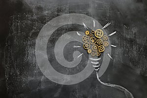 Education concept image. Creative idea and innovation. Vintage gears light bulb metaphor over blackboard