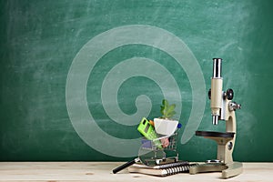 Education concept - microscope on the desk in the auditorium, blackboard background