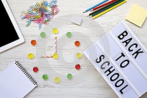 Education concept. Nine o`clock on watch. Clock made of colorful candies, `back to school` word on lightbox, accessories for st