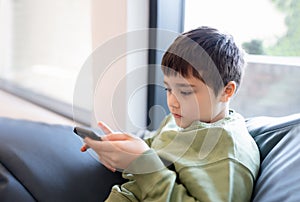 Education concept,School kid using mobile phone readying story from internet,Boy studying online learning at home,Child using cell