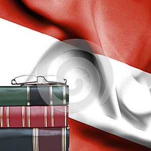 Education concept - Stack of books and reading glasses against National flag of Austria