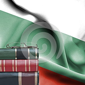 Education concept - Stack of books and reading glasses against National flag of Bulgaria