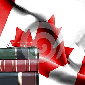 Education concept - Stack of books and reading glasses against National flag of Canada