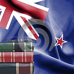 Education concept - Stack of books and reading glasses against National flag of New Zealand