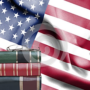 Education concept - Stack of books and reading glasses against National flag of United States of America