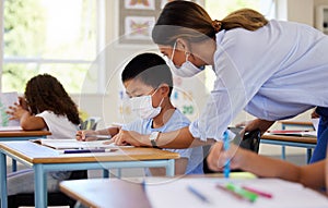 Education, covid and learning with face mask on boy doing school work in classroom, teacher helping student while