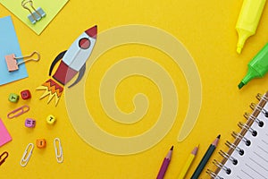 Education development concept. Back to school. Yellow background withschool supplies, notebook, rocket and sticky notes. Mock up.