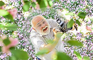 Education for elderly. Vintage camera. Photography hunt. Old happy man looking upwards at tree. Senior man holding