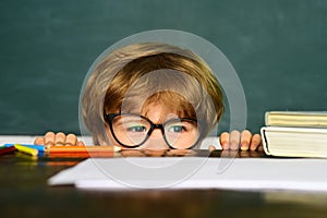 Education first. Funny little boy pointing up on blackboard. School and education concept. Little children at school