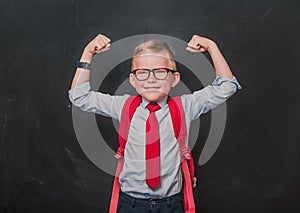 Education on fist class. Portrait of a schoolboy. Little pupil in uniform. Back to school. Funny strong kid in glasses