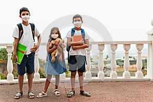 Education, healthcare and pandemic concept - group of elementary school students wearing protective medical face masks for