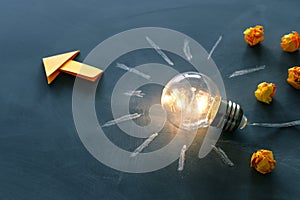 Education and leadership concept image. Creative idea and innovation. Light bulb as metaphor over blackboard