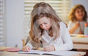 Education, learning and children concept. Little student girl pupil with book writing school test. Back to school. Happy