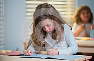 Education, learning and children concept. Little student girl pupil with book writing school test. Back to school. Happy