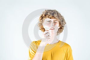 Education and learning concept. Smart curly-haired guy looks through a magnifying glass