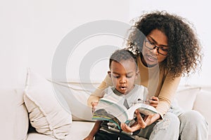 Education mother giving learning to little boy child interesting to read the book for smart kid, African black people family