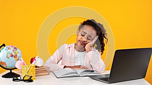 Tired black girl sitting at desk and reading book