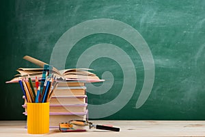 Education and reading concept - group of colorful books on the wooden table in the classroom, blackboard background