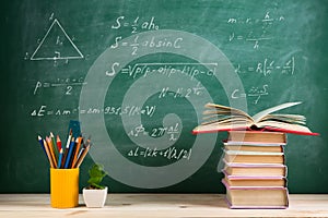 Education and reading concept - group of colorful books on the wooden table in the classroom, blackboard background