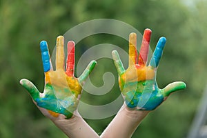 education, school, art and painitng concept - little student girl showing painted hands at school on grass