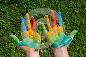 education, school, art and painitng concept - little student girl showing painted hands at school on grass