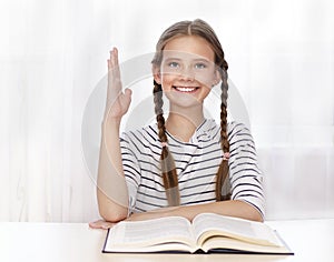 Education and school concept. Cute little student girl studying and raising hand