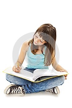 Education and school concept - little student girl sitting on floor and reading book