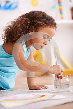 Education, school or girl painting a rainbow on classroom floor for creative, learning or child development. Paper
