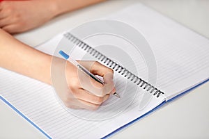 Hands of student girl with pen writing to notebook